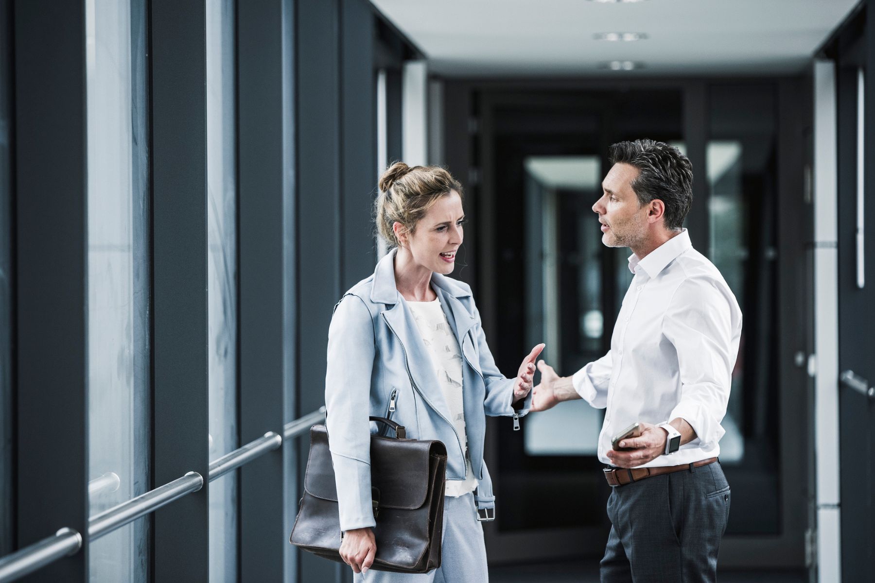 Two coworkers argue in a corridor