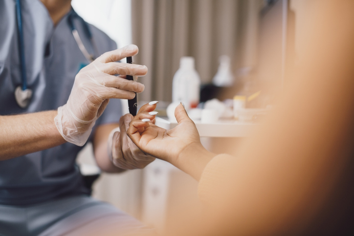 A doctor testing a patient's blood sugar levels using a finger prick test