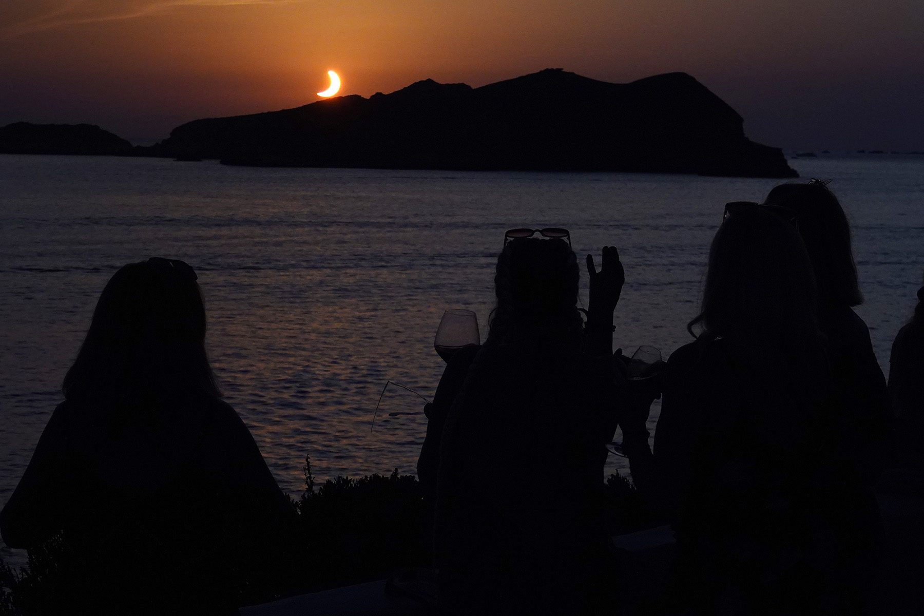 crescent sun setting behind an island
