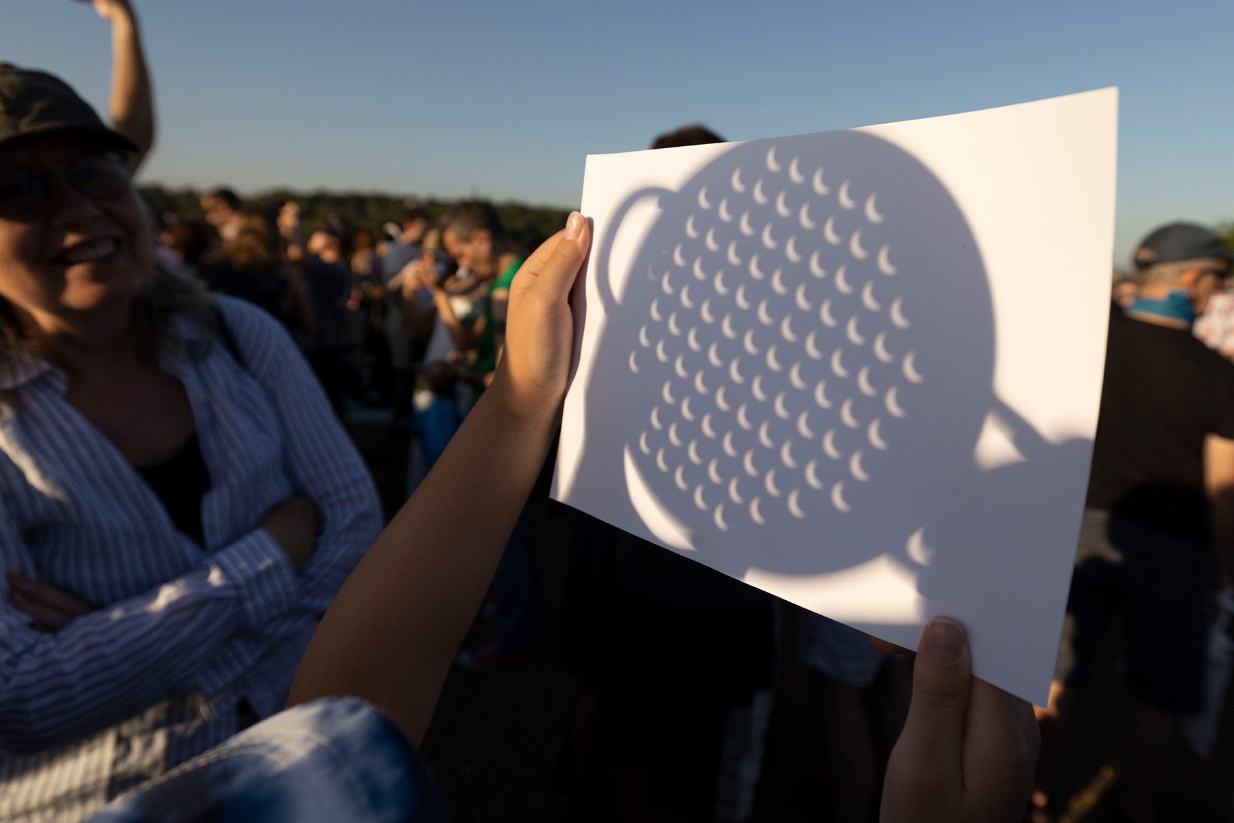 Shadow of a colander on a piece of paper. The holes look like little crescents