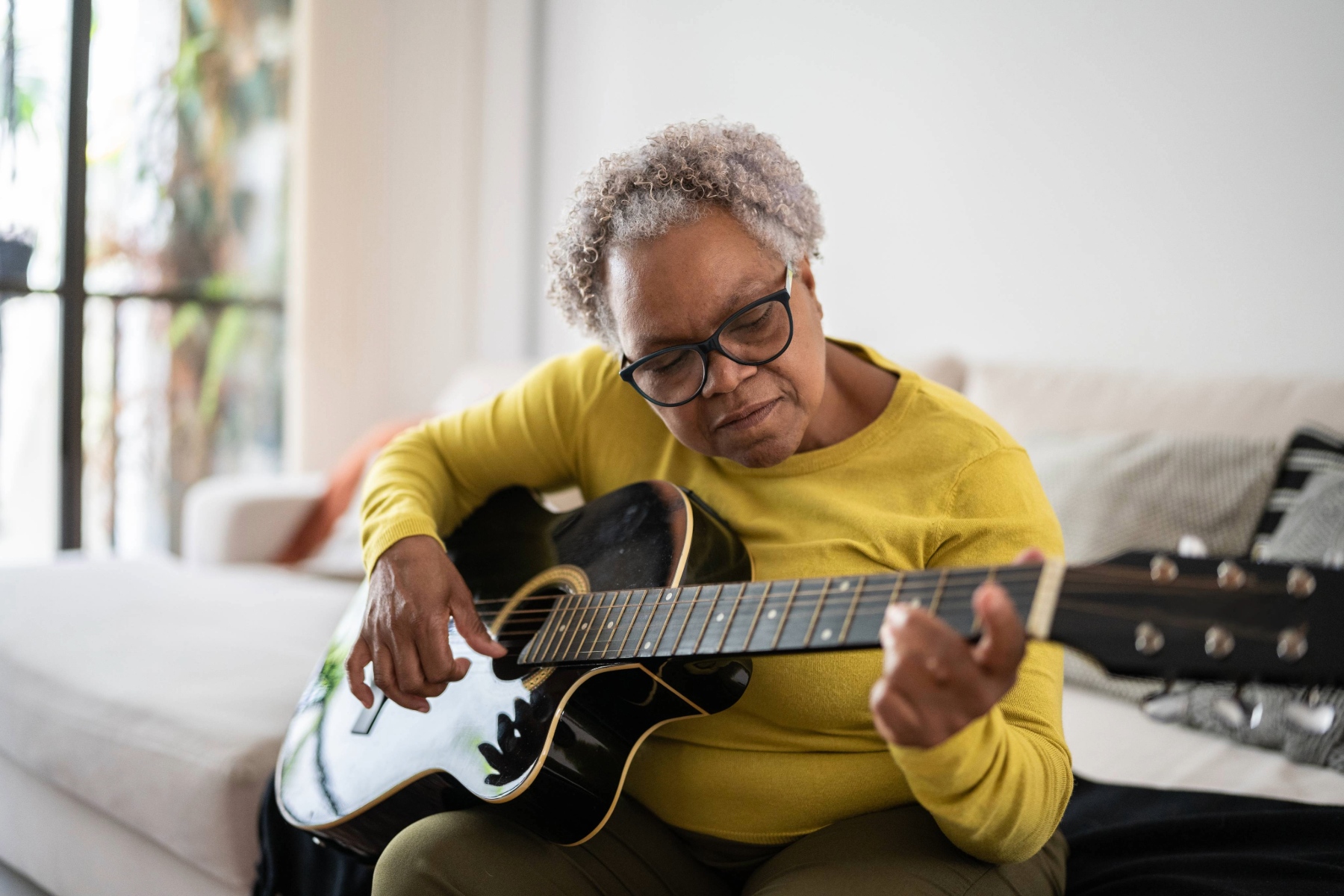 Senior woman playing the guitar at home