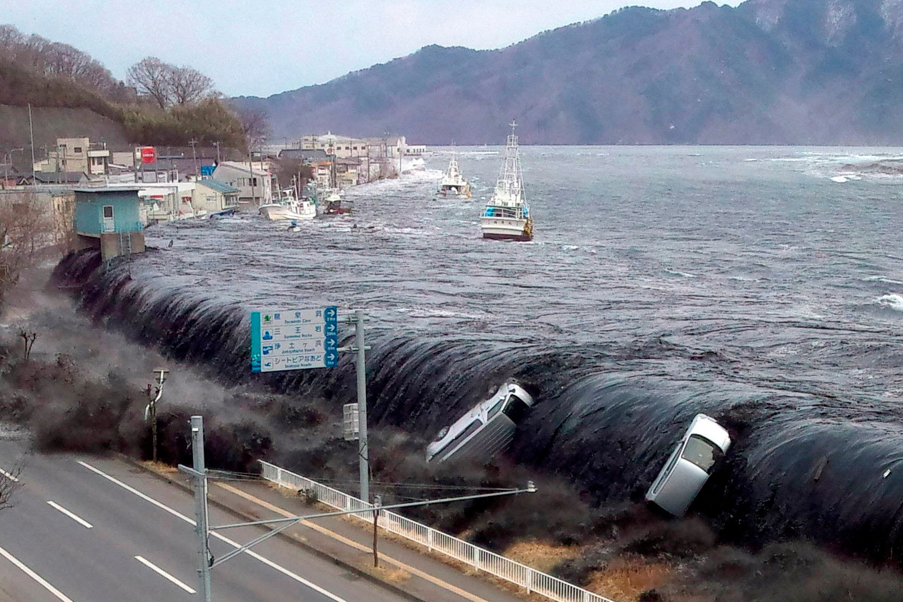 Tsunami wave hitting a road and moving cars