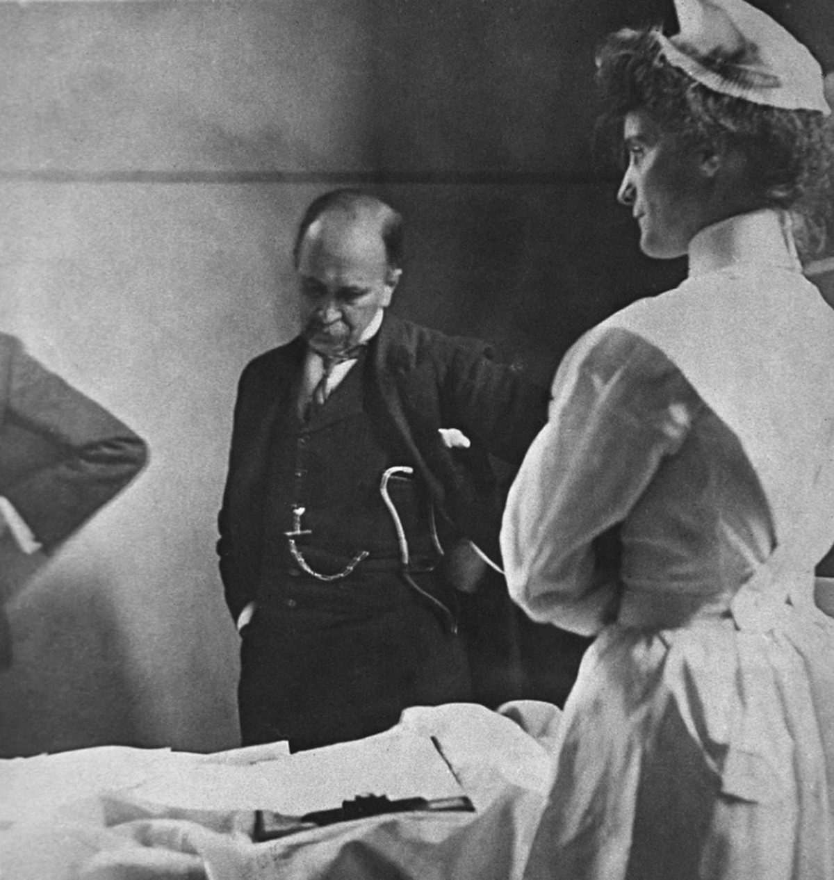 Sir William Osler reading a patient's chart at bedside as a nurse watches