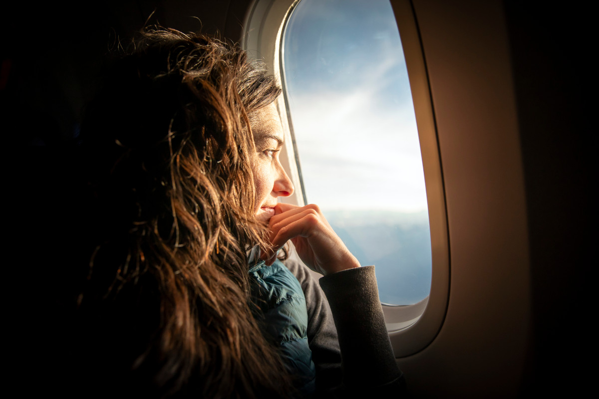 A woman looking out of an aeroplane window at sunrise