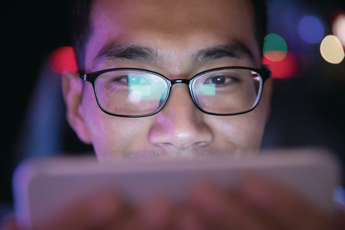 Close up image of a person wearing glasses watching something on their phone