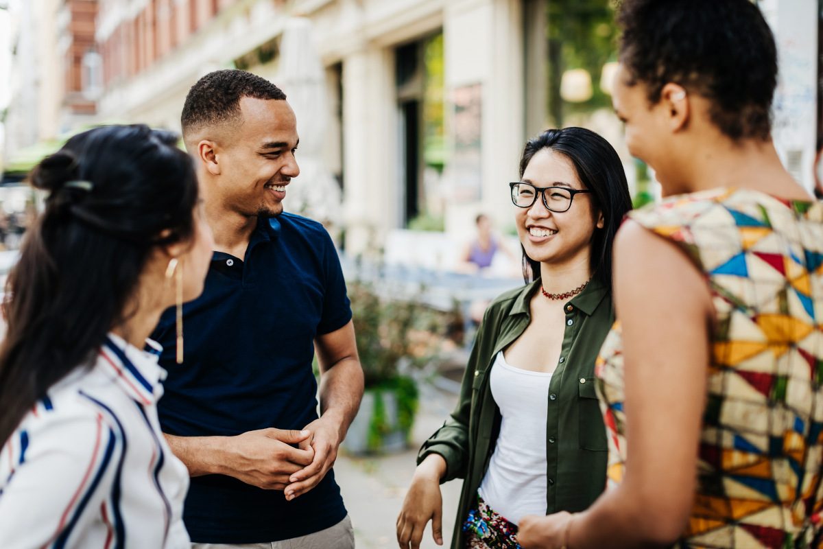 A group of friends hanging out and chatting outside a cafe in the city