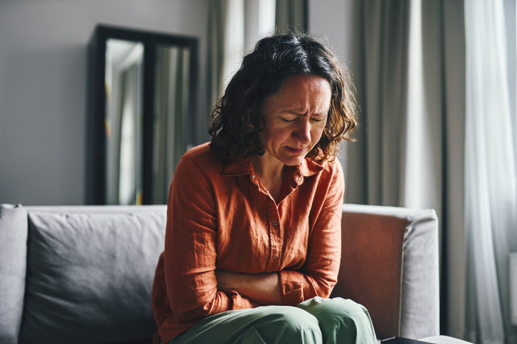 A woman clutches her abdomen in pain
