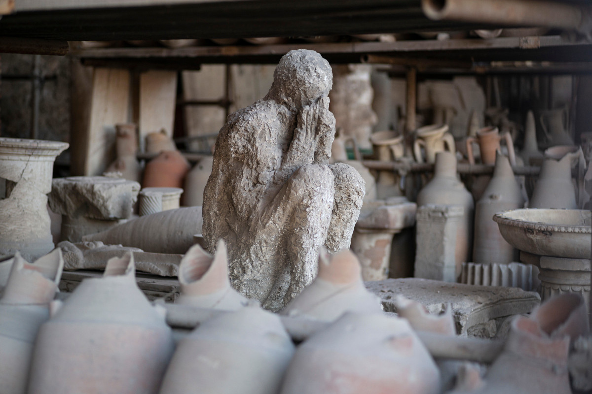A plaster cast of a victim who died in the eruption of Mount Vesuvius surrounded by remarkably preserved artefacts