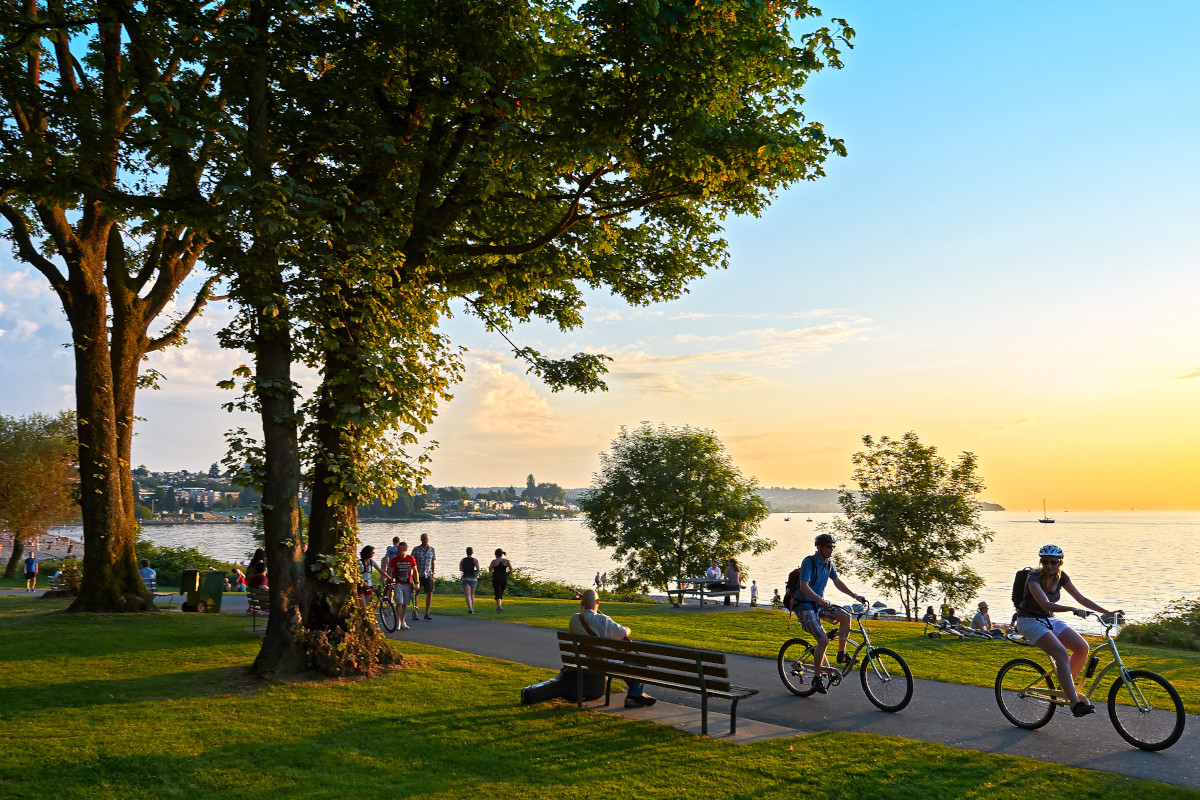 Young couple cycling, others walking or jogging late afternoon and enjoying the sunset