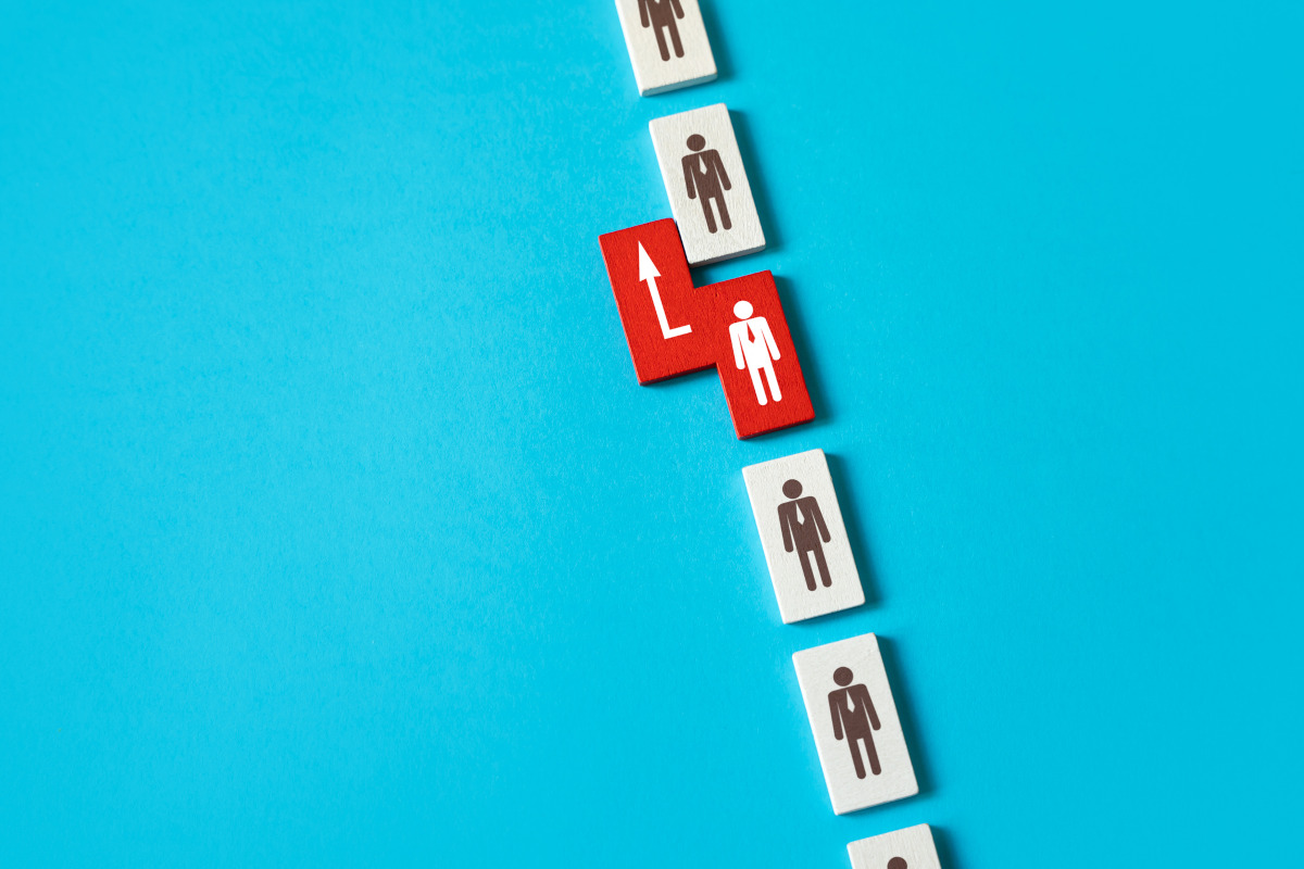 CGI illustration, white pieces with a person wearing a tie on each. One red piece has an advantage, moving ahead of those in the line above