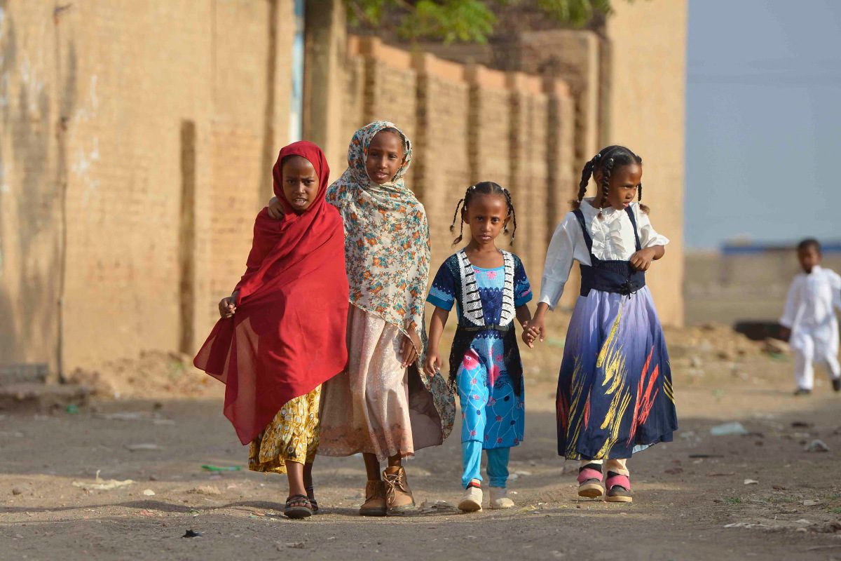 A group of young children holding hands in a conflict zone