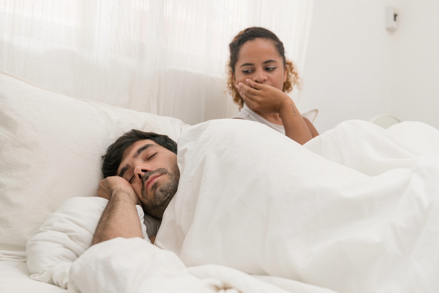 Anxious woman in bed looking at partner