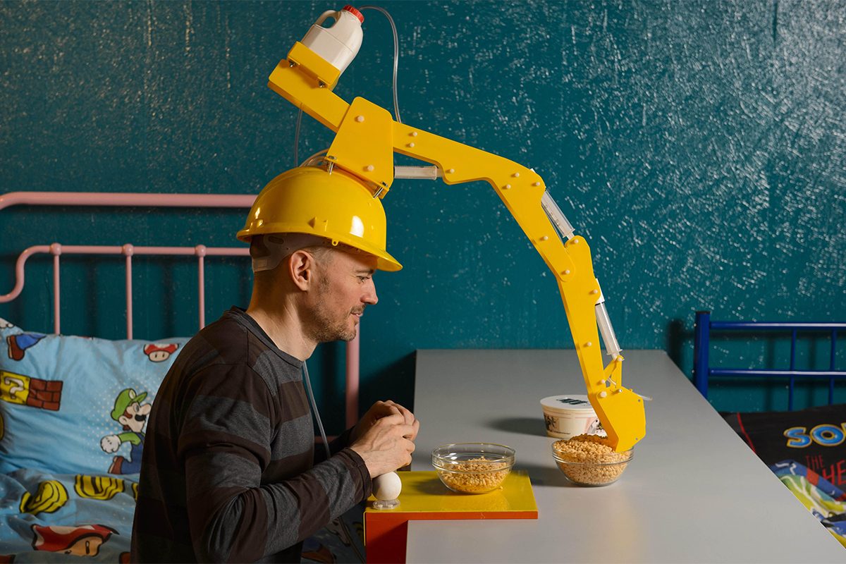 Man wearing robotic arm on head.