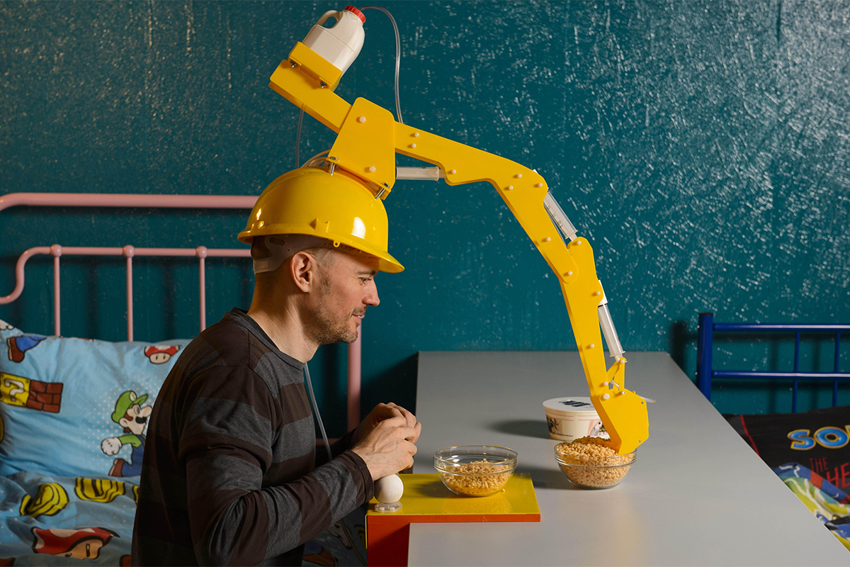 Man wearing robotic arm on head.
