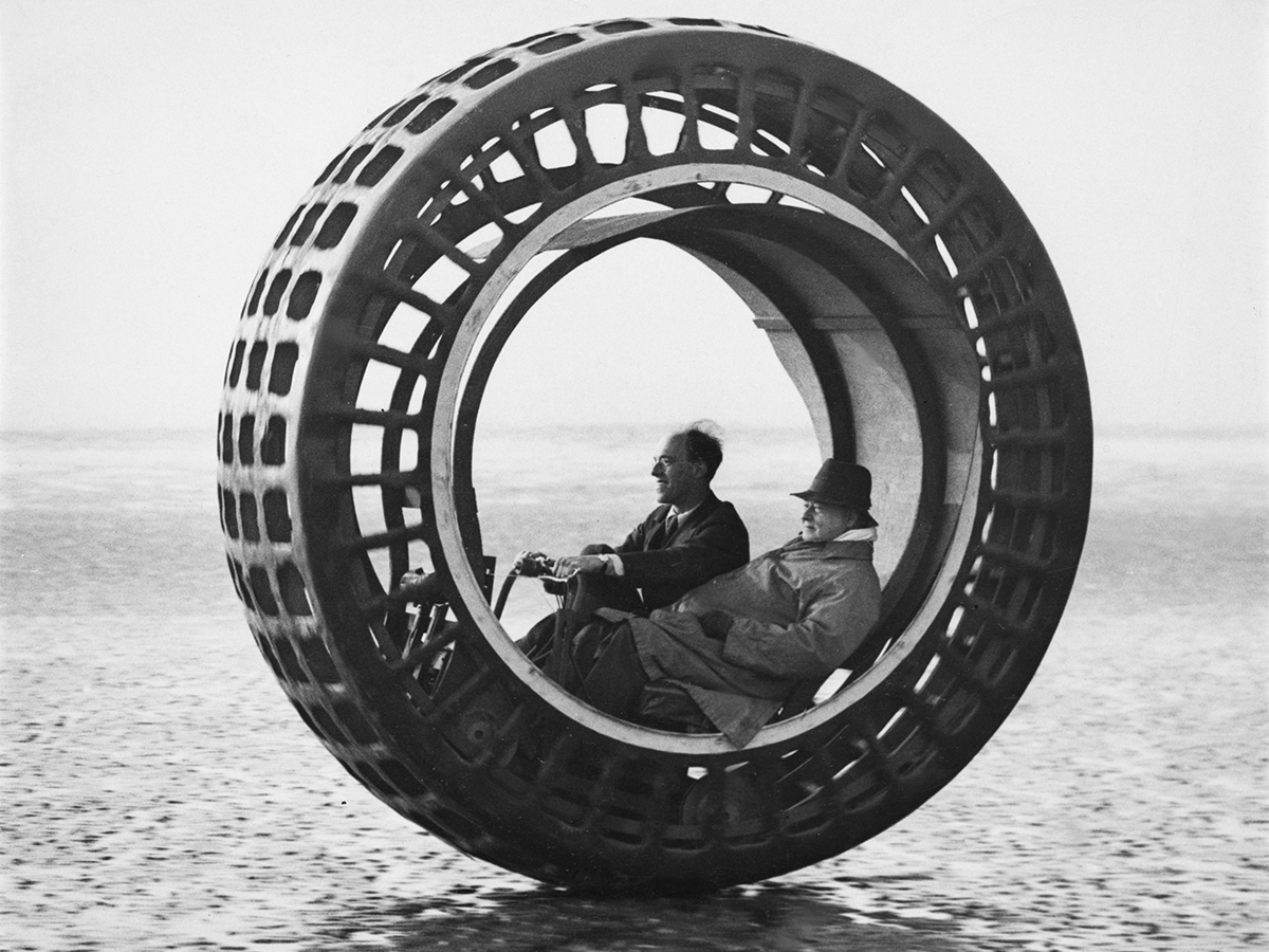 Two people sit in wheel car.