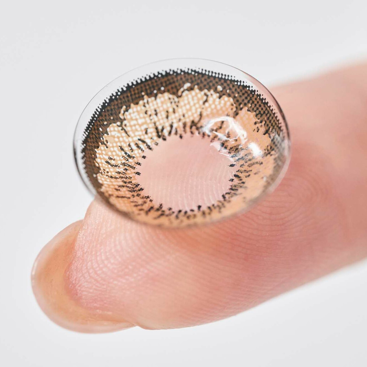 Image of a nanoparticle-coated contact lens on a person's fingertip