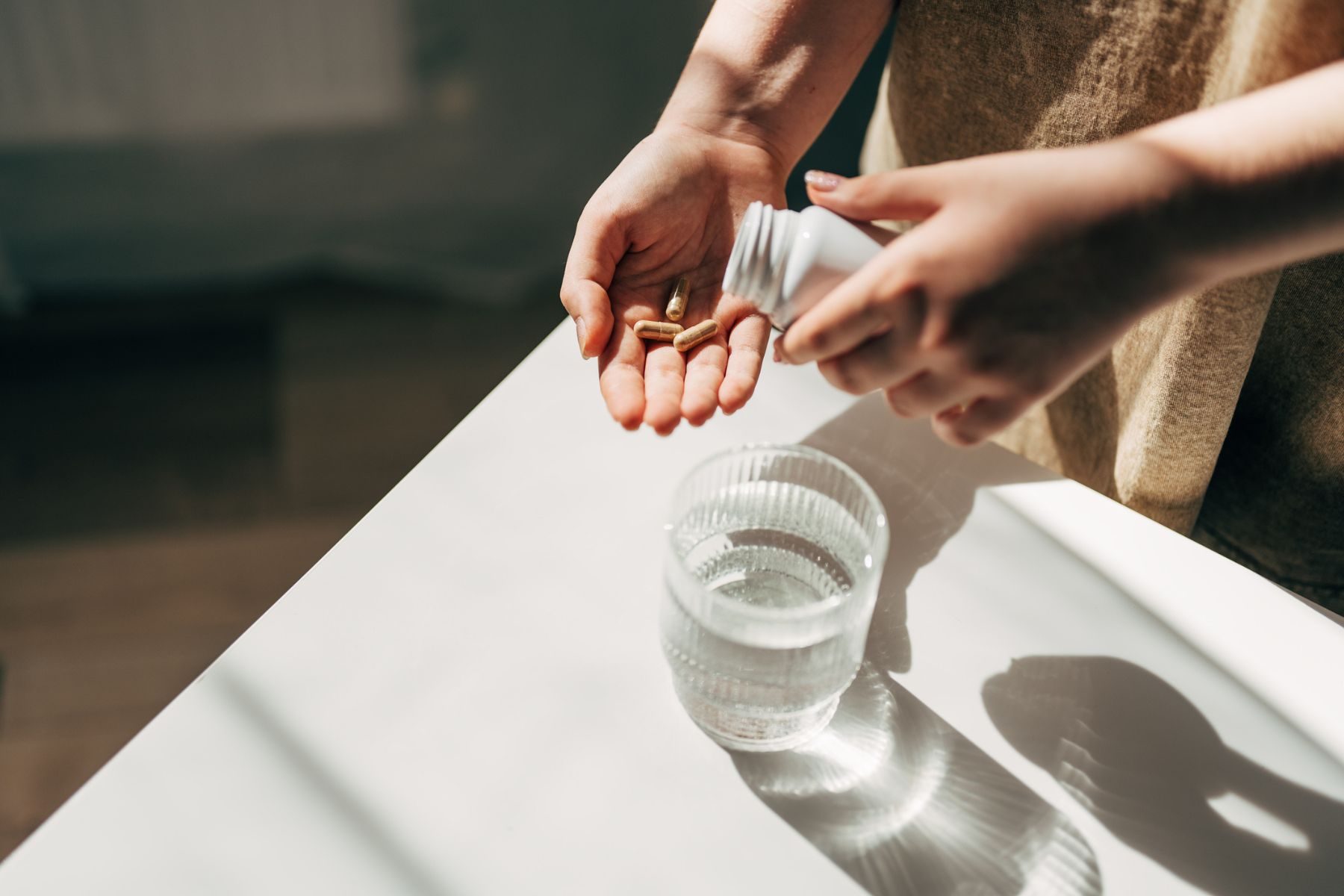 A person taking a pill with a glass of water
