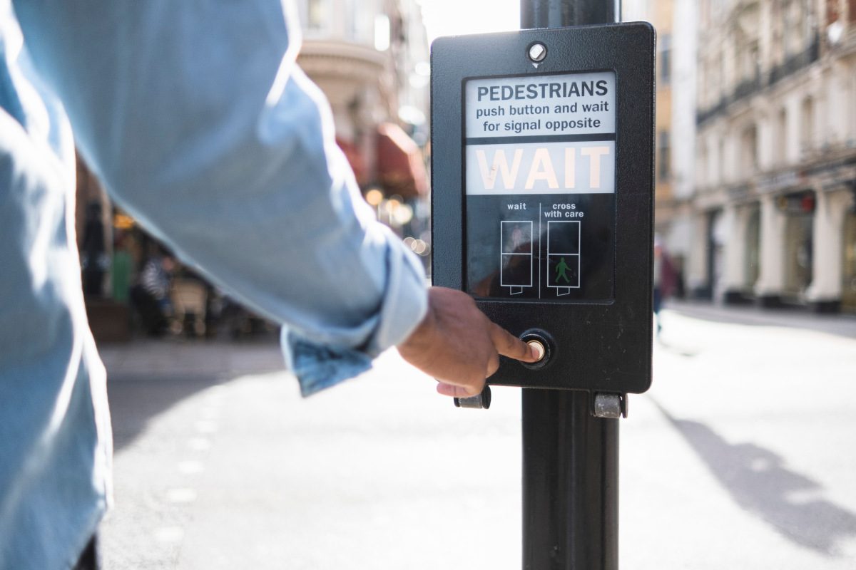 Man pushing button on traffic signal in city