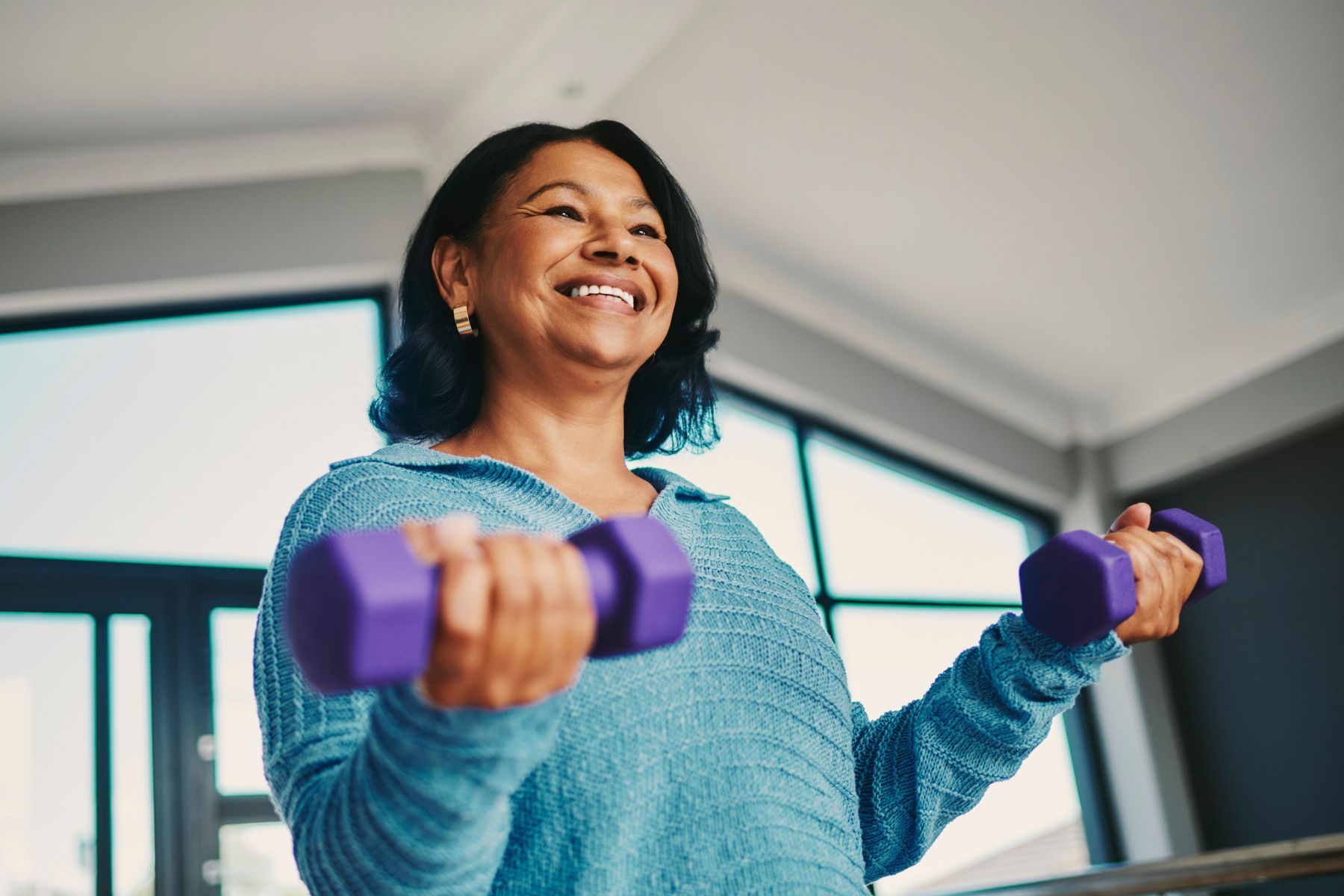A woman lifts small weights at home