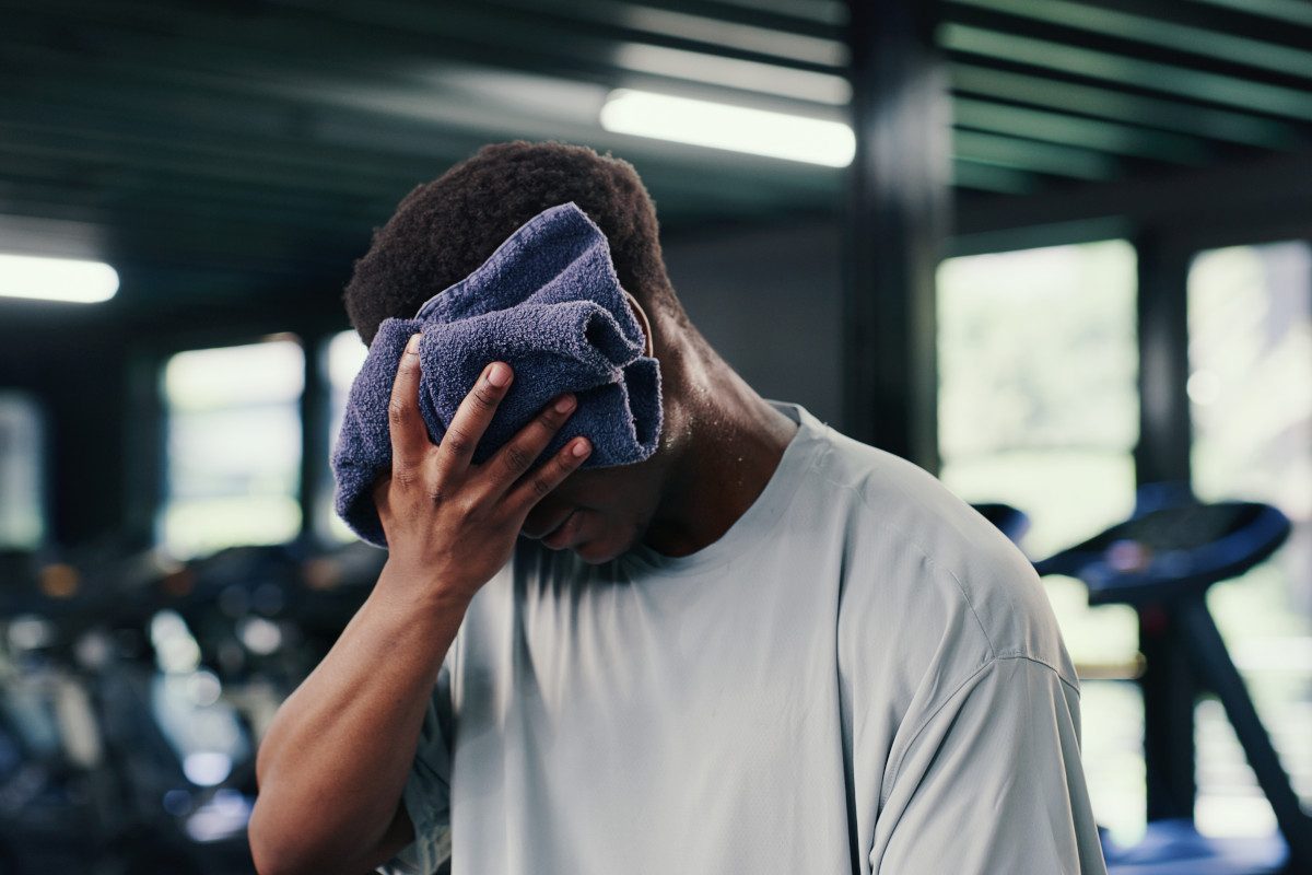Photo of a person holding a towel to their face at a gym, wiping sweat away