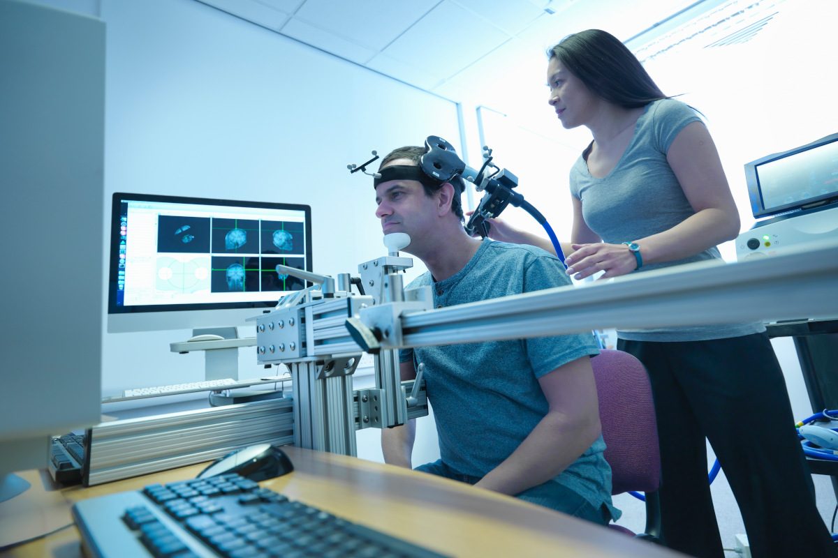 Scientist conducting transcranial magnetic stimulation (TMS) experiment on patient