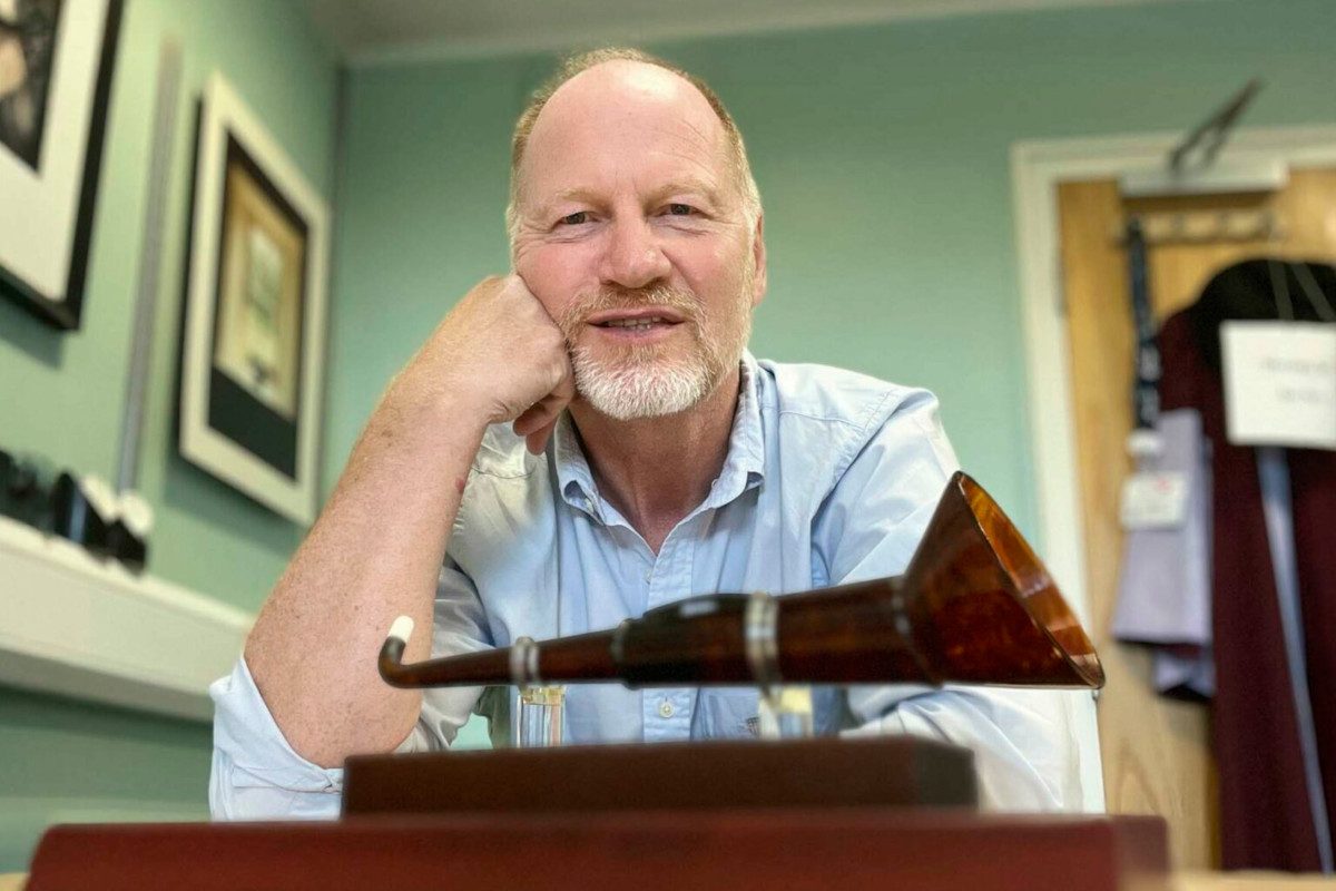 Photo of Prof Kevin Munro sat behind an old-fashioned hearing aid