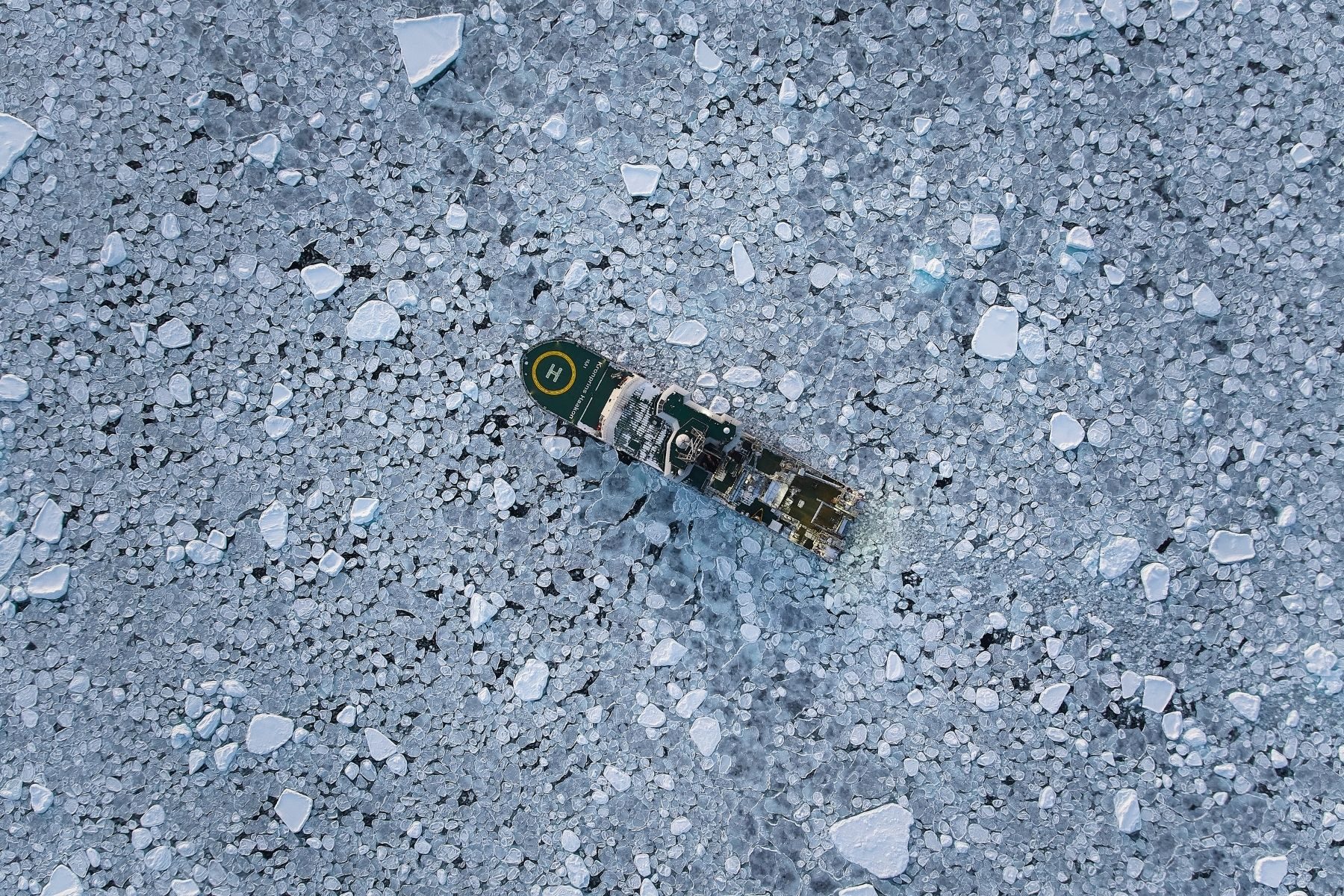 An aerial view of a large boat sailing through ice