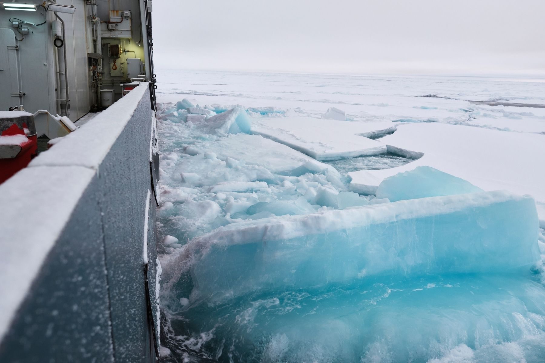 A view from a boat looking out onto broken ice and a white sky