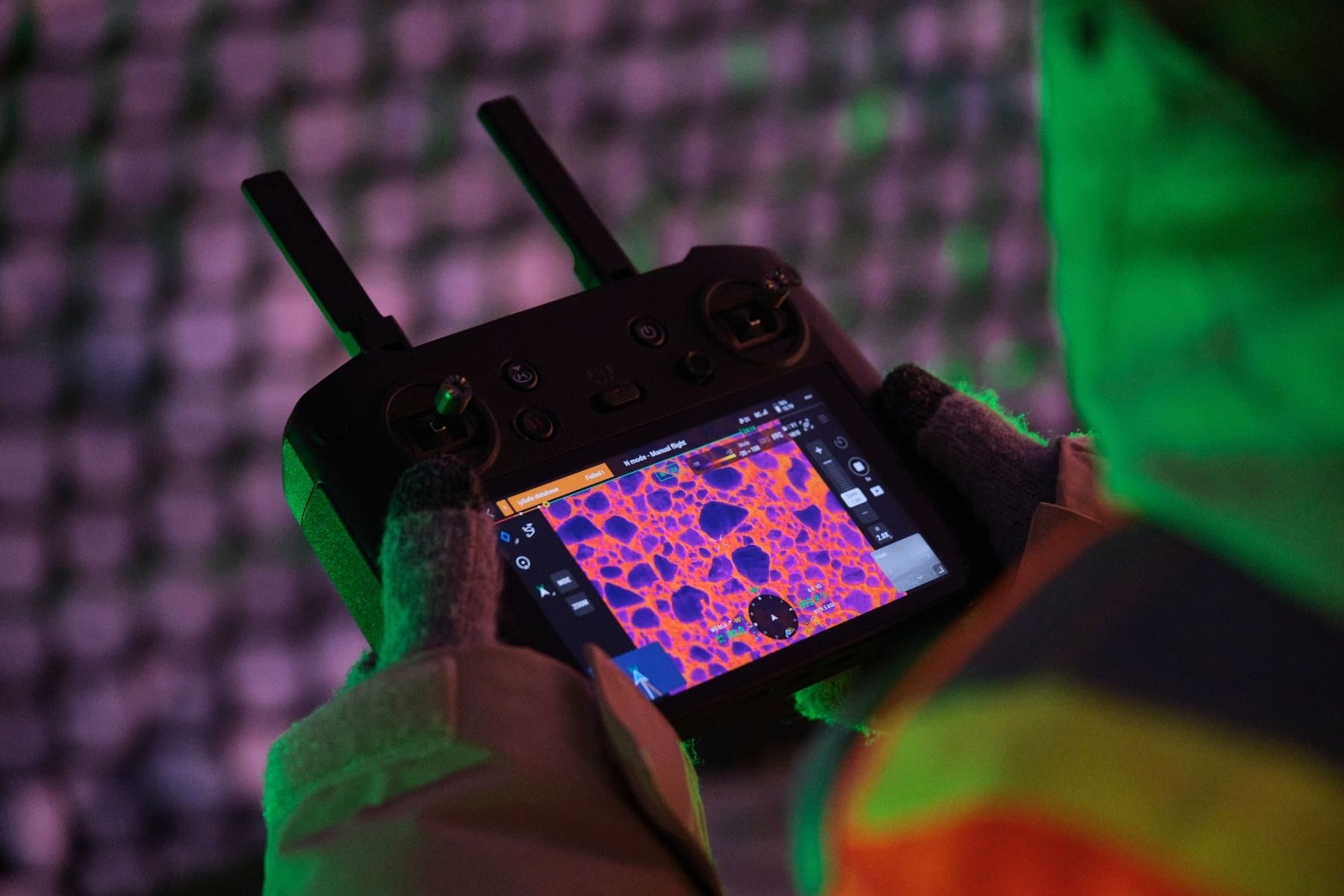Gloved hands hold a remote control showing pink and blue heat spots