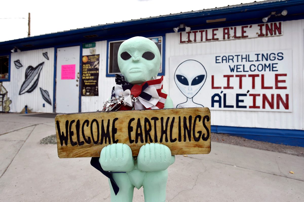 An alien-like statue displays a sign welcoming guests to the Little A'le' Inn restaurant and gift shop