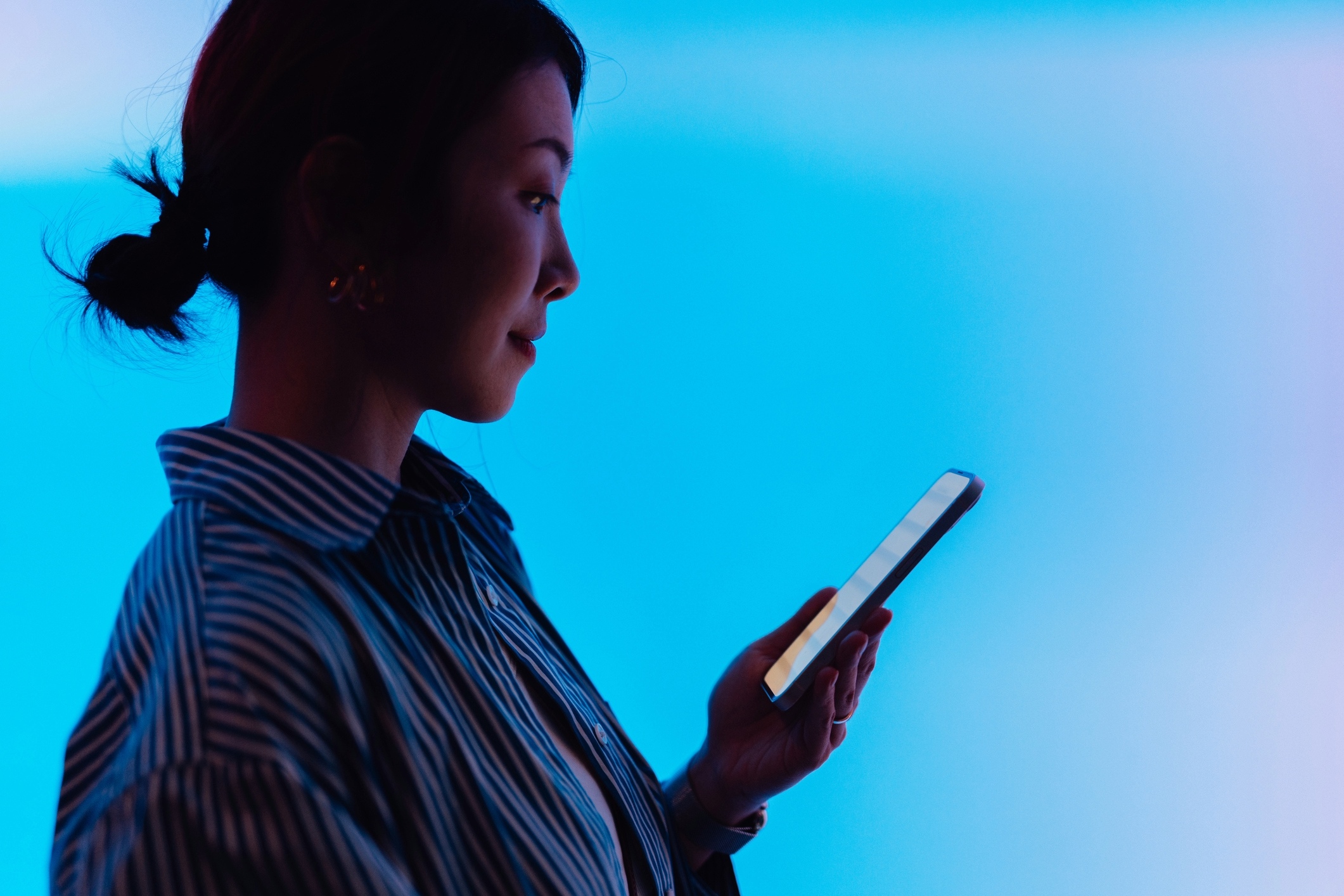Woman holding phone in front of blue light.