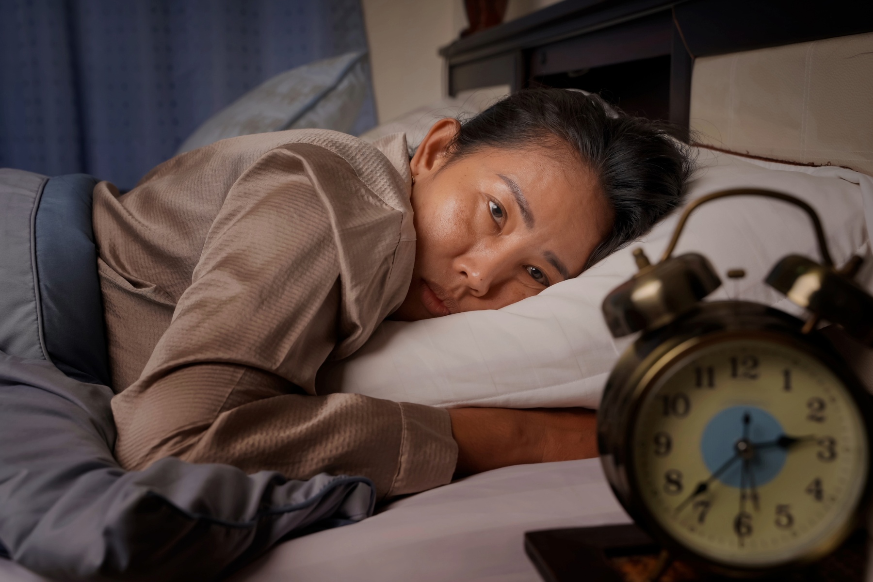 woman in bed looking at the clock