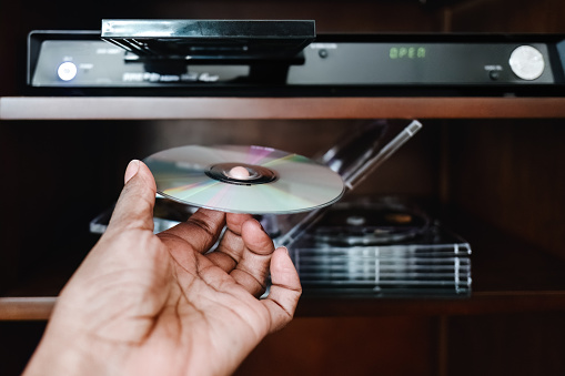 Close-up of hand holding CD towards a CD player system