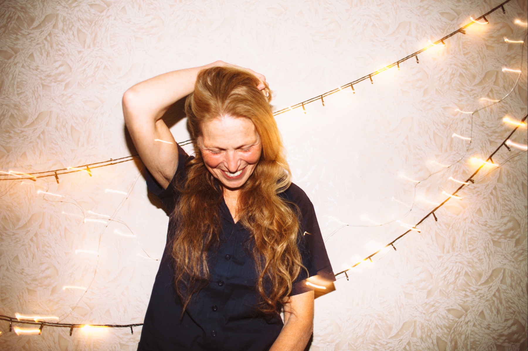 Portrait of happy senior woman standing by the wall with Christmas lights.