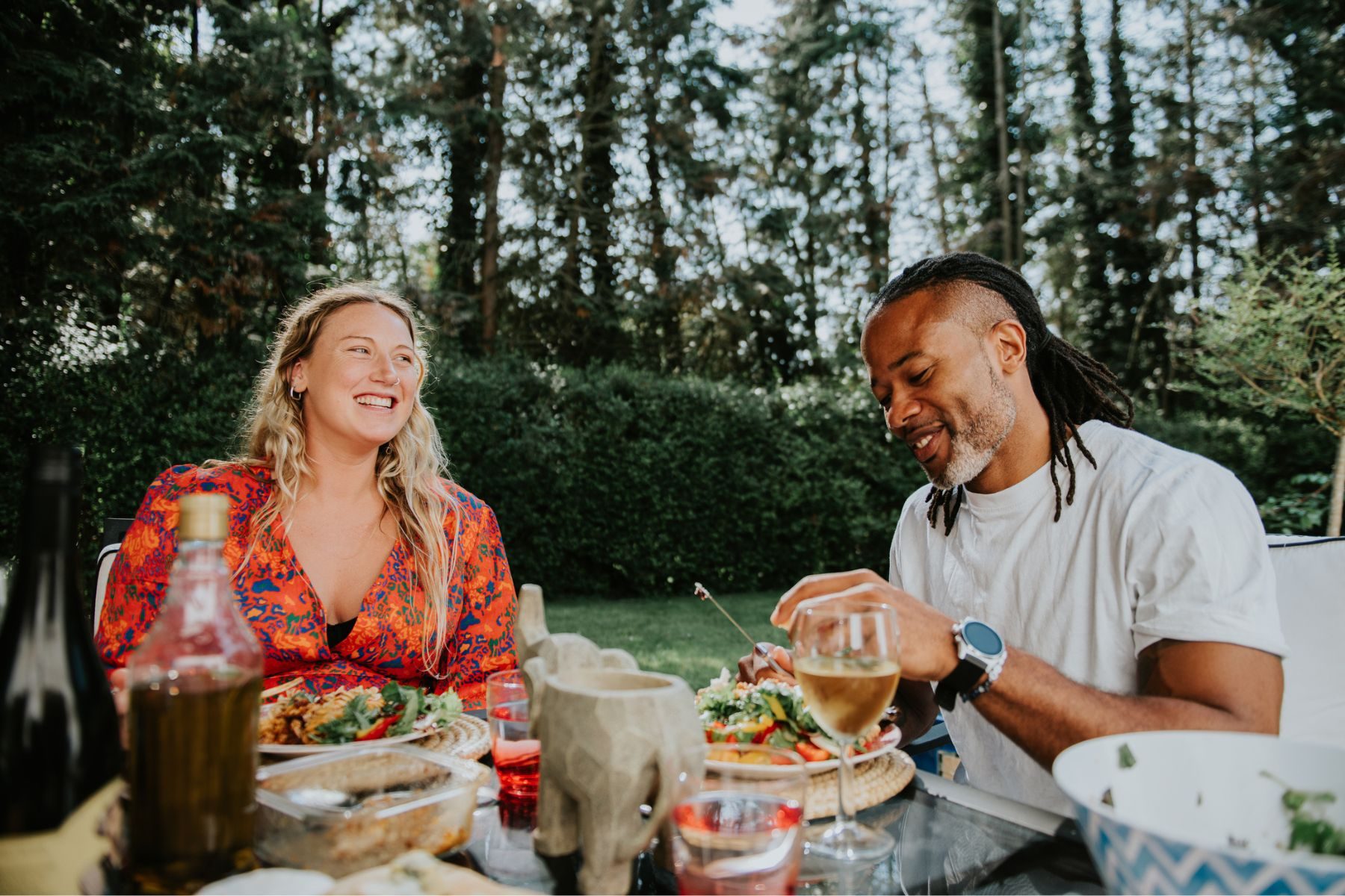 Two people sit and eat outside