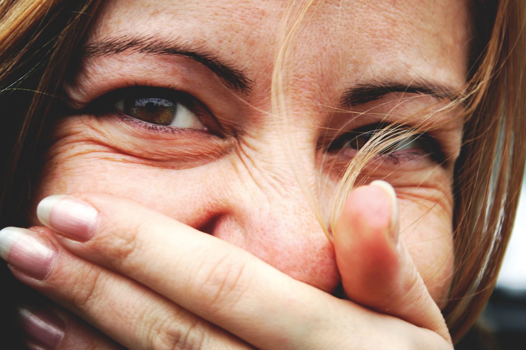 A woman covering her mouth with a hand, laughing