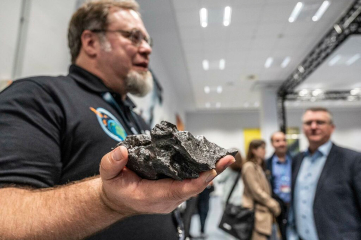 An ESA scientist holds a piece of meteorite, which is in focus, the rest of the photo is blurred